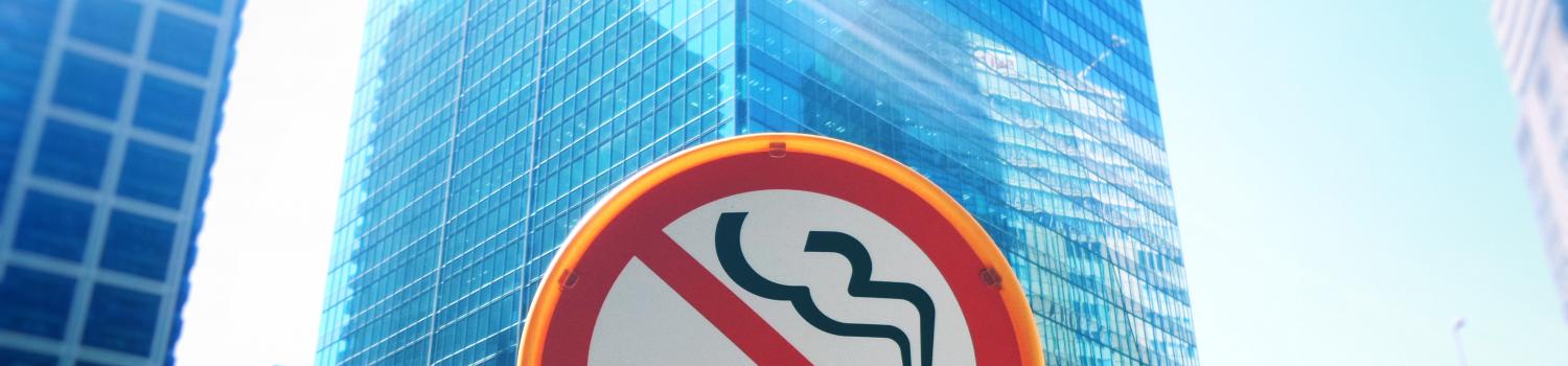 A street sign with a red circle and line over an image of a lit cigarette