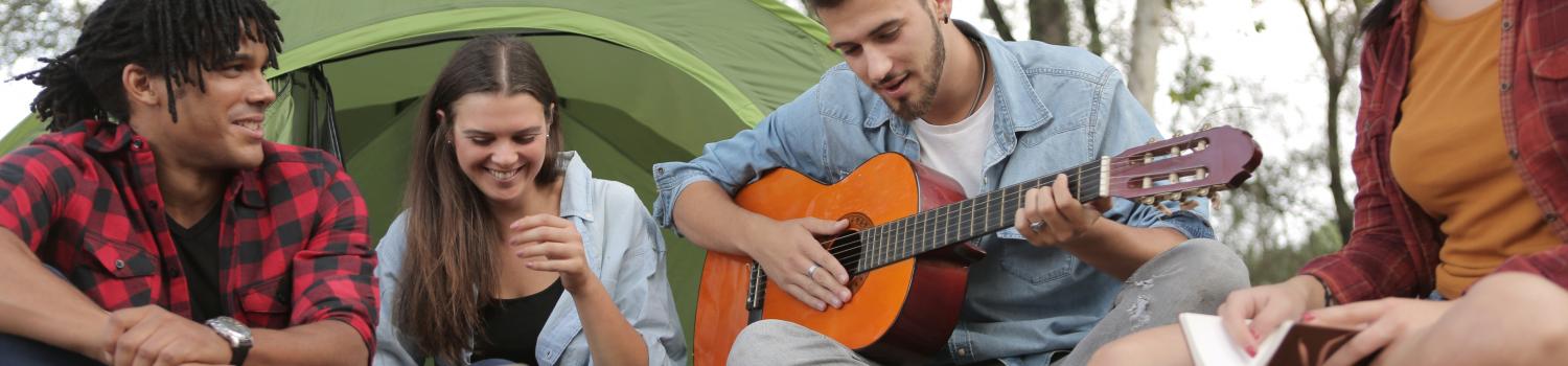 people singing outside with guitar and tent